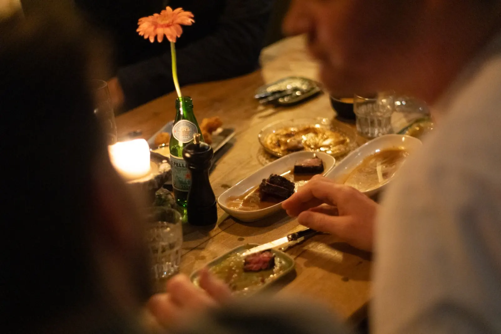 Een gerbera in een flesje op een volle tafel